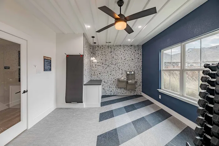 Modern fitness room with stylish lighting, sleek water station, and bold accent wall, perfect for energizing workouts.
