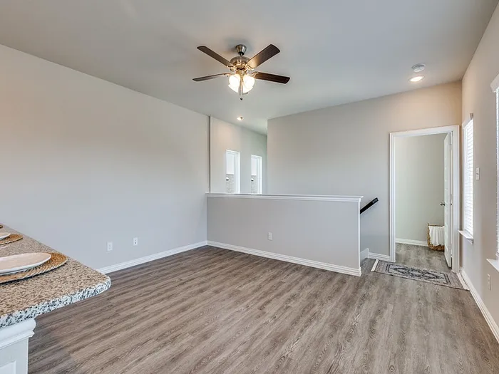 Bright open-concept living space with elegant wood flooring and ceiling fan, perfect for cozy family gatherings.