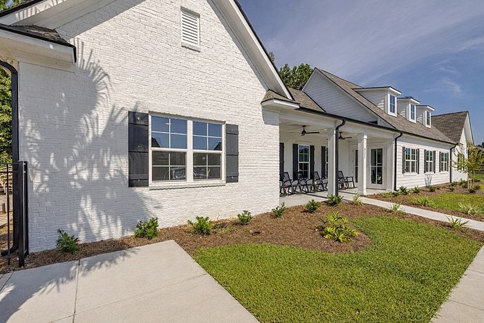 Charming and modern white brick house with inviting porch and lush green lawn.