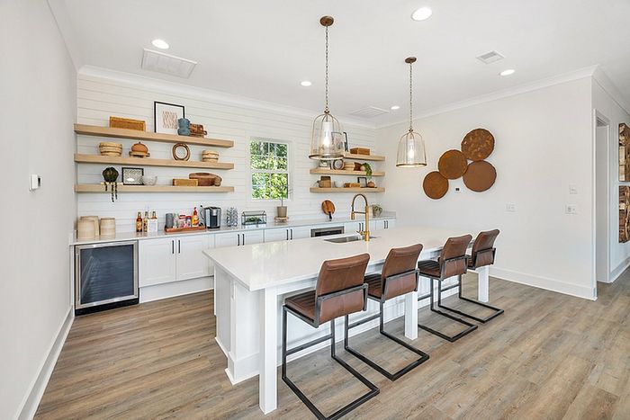 Contemporary kitchen with sleek white cabinetry, stylish open shelving, and a spacious central island with chic leather bar stools, perfect for modern living.