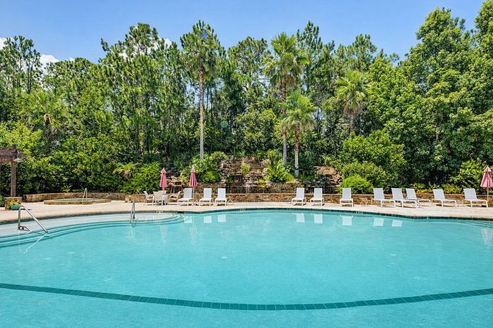 Stunning resort-style swimming pool surrounded by lush greenery and elegant lounge chairs, perfect for relaxation and outdoor enjoyment.