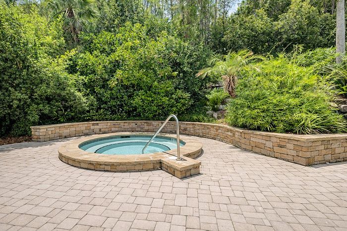 Inviting outdoor hot tub set amidst lush greenery and elegant stonework, perfect for relaxation.