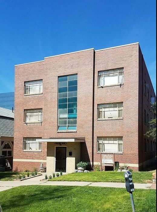 Elegant brick apartment building with large windows and a well-maintained lawn.