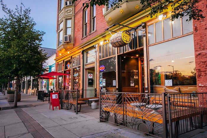 Charming urban street with vibrant storefronts and outdoor seating at dusk.