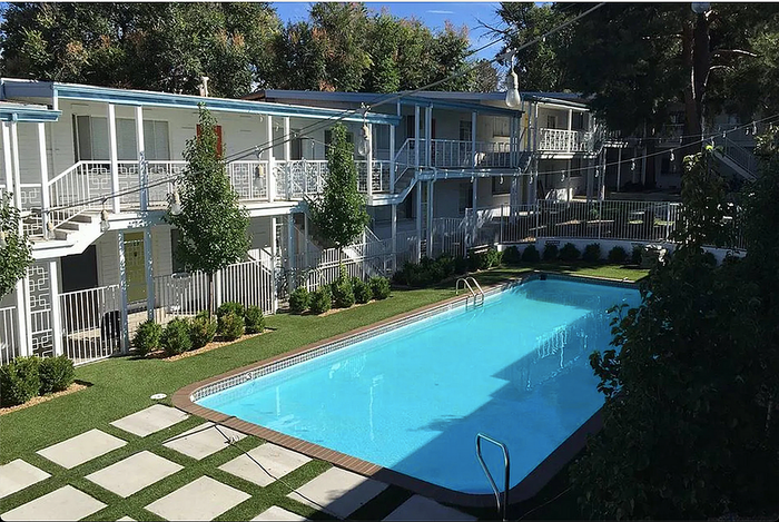 Serene apartment complex with a sparkling pool and lush greenery.
