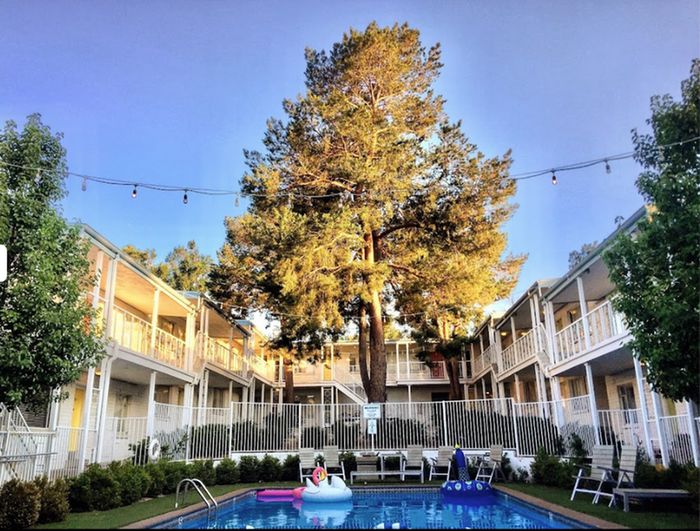 Serene courtyard featuring a sparkling pool, surrounded by two-story apartment buildings and lush greenery.