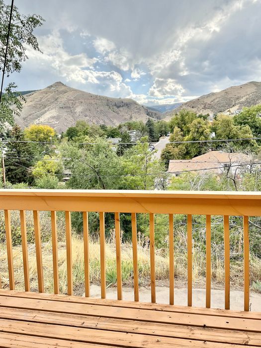 Charming wooden balcony overlooking a beautiful mountain landscape under a partly cloudy sky.