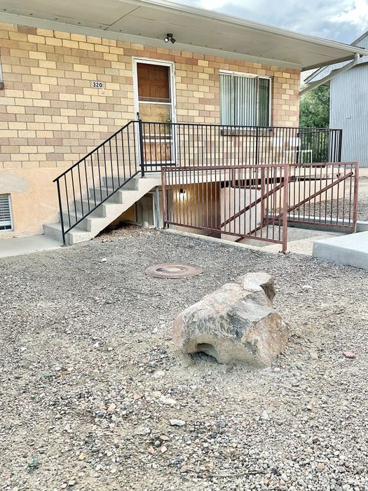 Inviting apartment entrance with brick exterior, front steps, and a secure railing.