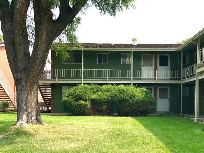 Cozy two-story apartment exterior with lush greenery and a welcoming courtyard.