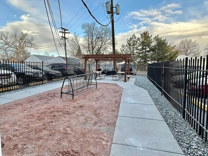 Inviting outdoor space with a pergola and seating, surrounded by a quaint garden pathway and secure fencing.