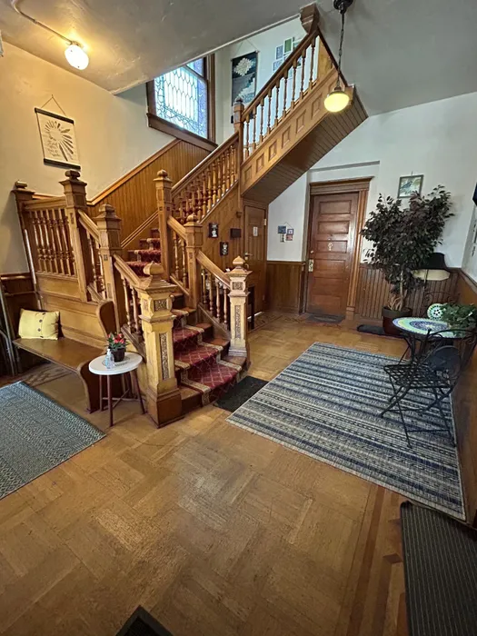 Elegant wooden staircase with intricate detailing in a cozy, vintage-style interior setting.