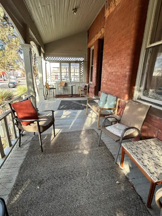 Cozy veranda with assorted seating, surrounded by classic brick and serene views.
