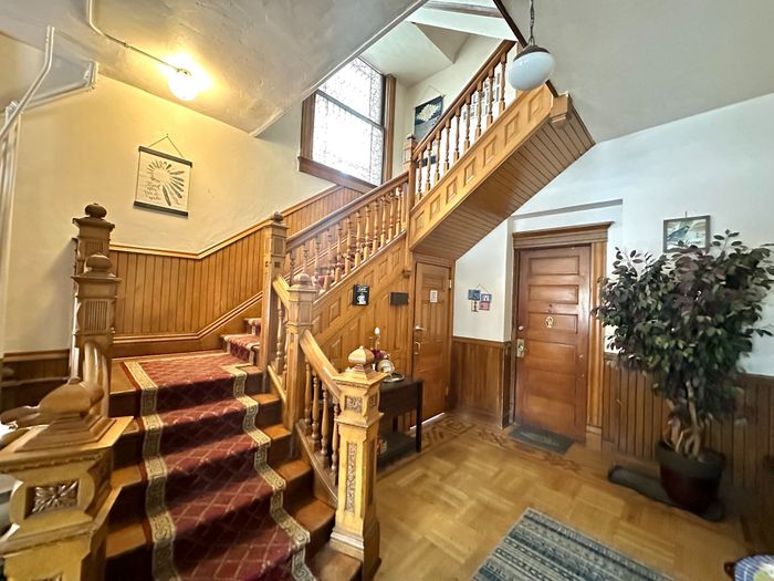 Inviting entrance with a wooden staircase, classic paneling, and decorative elements in a charming apartment.