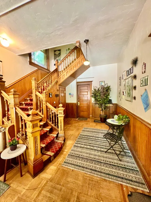 Inviting entryway with classic wooden staircase, plush carpeting, and cozy seating area.