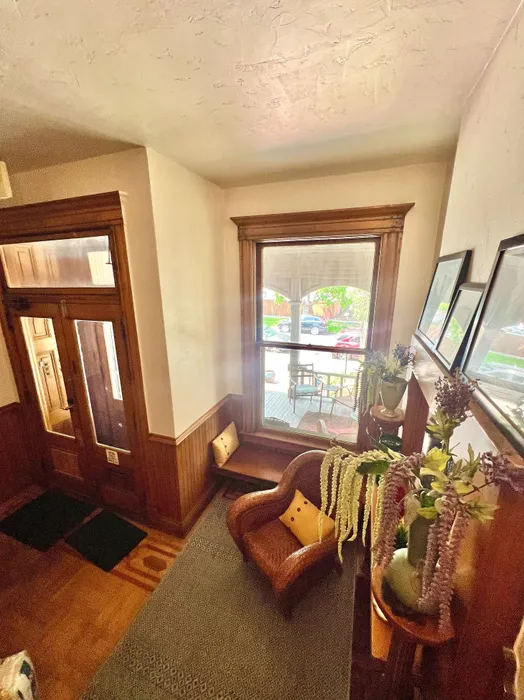 Inviting entryway with large window, wooden accents, and colorful plants.