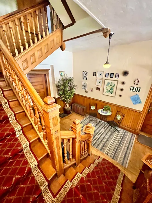 Inviting entrance featuring a classic wooden staircase with ornate railings and a cozy seating area.