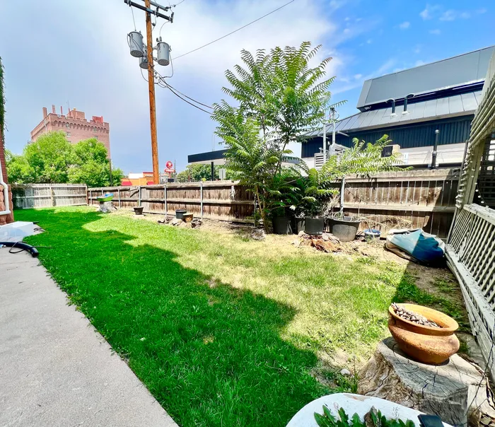 Inviting backyard with lush green lawn, a mature tree, and a quaint garden patio.