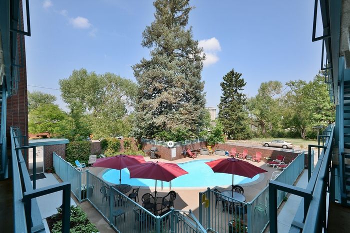 Inviting courtyard with a sparkling pool, colorful umbrellas, and lush greenery.