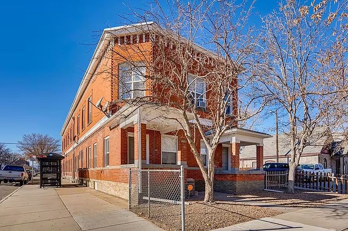 Elegant red-brick apartment building with charming architectural details on a sunny day.
