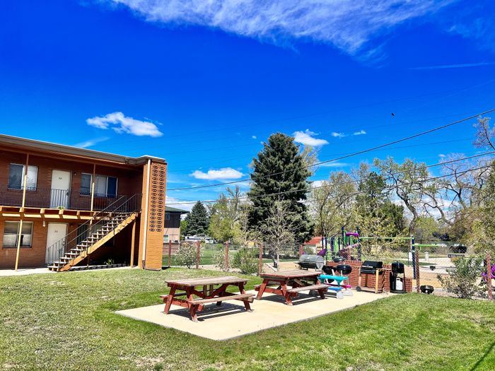 Inviting outdoor space with picnic benches and a play area set against a bright blue sky.