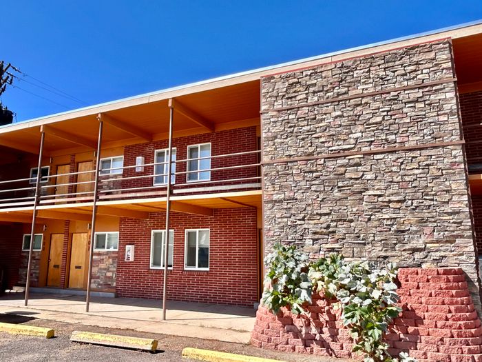 Charming two-story brick apartment building with a modern stone accent wall and inviting double-door entry, basking in bright sunlight.