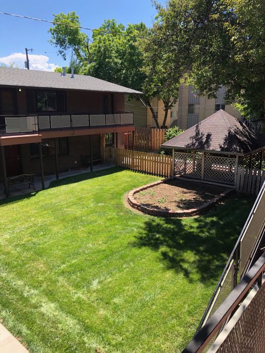 Charming backyard featuring lush green lawn, cozy wooden gazebo, and a spacious patio area perfect for outdoor relaxation.
