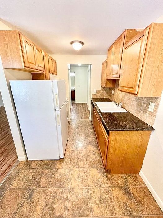 Charming kitchen with granite countertops, light wooden cabinets, and a classic tile floor, creating a warm and inviting cooking space.