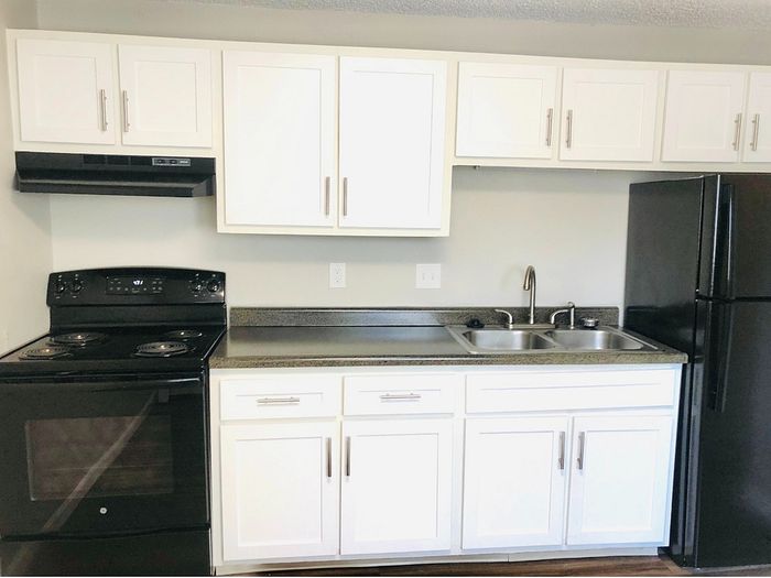 Modern kitchen with sleek white cabinets, black appliances, and a spacious countertop, perfect for culinary creativity.