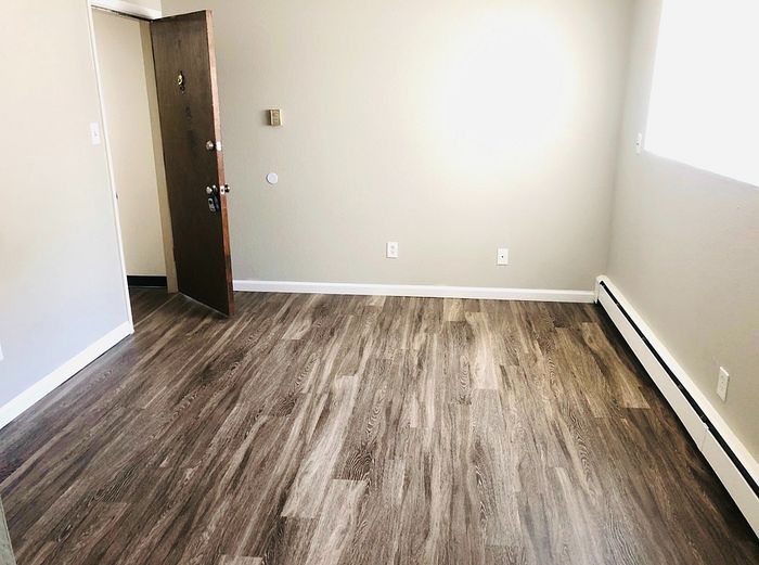 Inviting room with elegant wood flooring, abundant natural light, and freshly painted walls, perfect for a cozy living space.