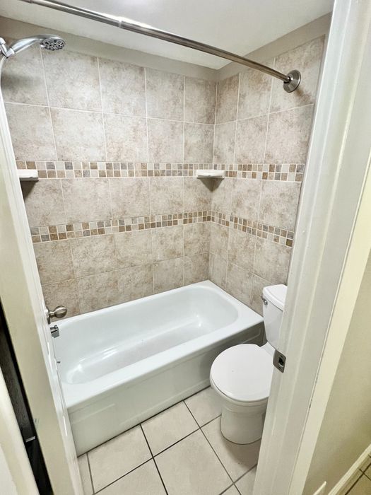 Elegant bathroom showcasing modern beige tile, a cozy bathtub, and a clean, minimalist design.