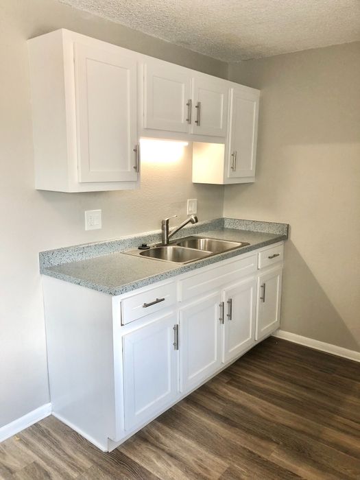 Modern kitchen space featuring sleek white cabinets, granite countertops, and a stainless steel sink with elegant fixtures.