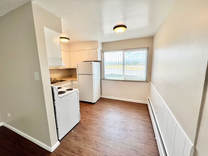 Bright and modern kitchen with sleek white cabinetry, cozy dining area, and large window offering scenic views.