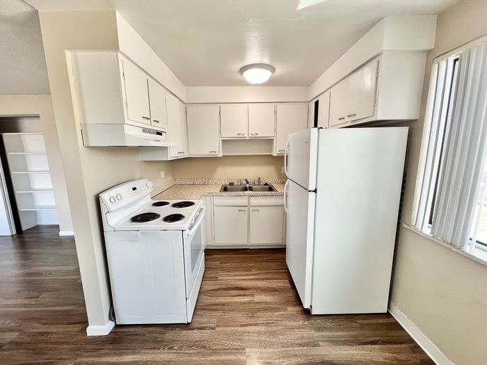 Bright and inviting kitchen with white cabinetry, modern appliances, and wood-style flooring, perfect for culinary creativity.