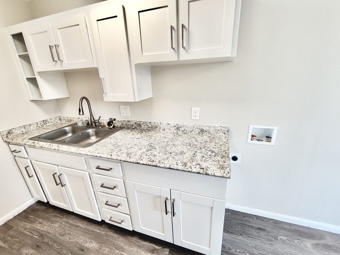 Modern kitchen with sleek white cabinets, elegant granite countertops, and a double stainless steel sink.