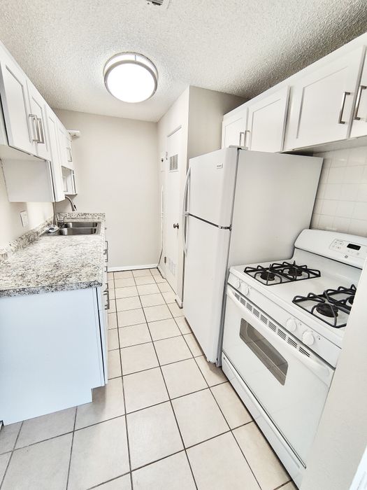 Bright and modern kitchen featuring sleek white cabinets, granite countertops, and a cozy layout perfect for culinary creativity.