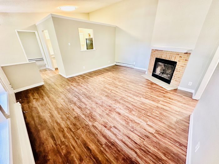 Inviting living area with elegant wood flooring and a cozy brick fireplace, perfect for relaxing and entertaining.