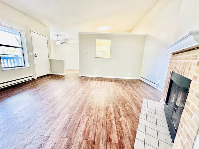 Inviting living room with elegant wood flooring, a cozy fireplace, and bright natural light creating an airy atmosphere.