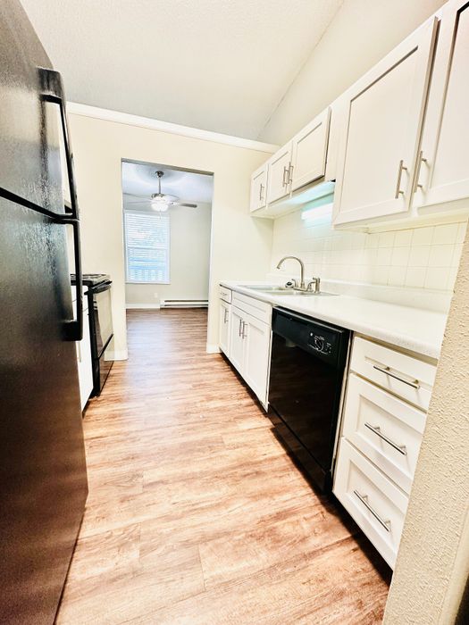 Bright and inviting kitchen with sleek white cabinets, modern appliances, and warm wooden flooring, reflecting a contemporary and spacious design.