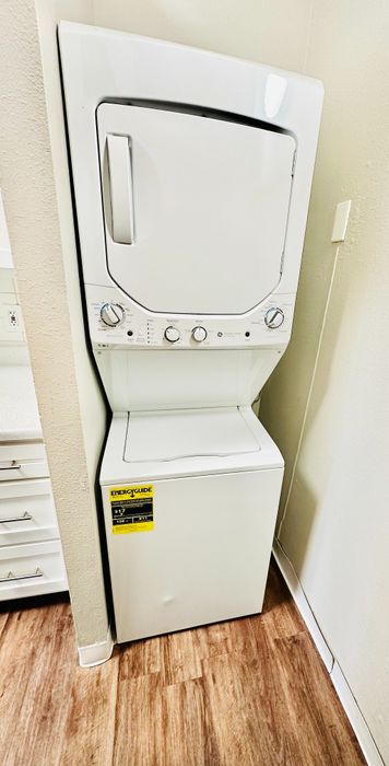 Efficient and stylish stacked washer and dryer unit in a modern apartment, complemented by sleek wooden flooring.