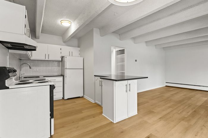 Bright modern kitchen with sleek white cabinetry, elegant backsplash, and open layout with hardwood floors.