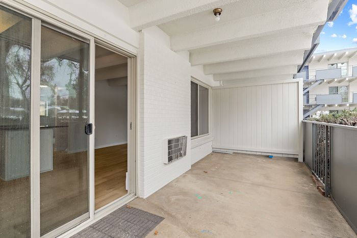 Inviting apartment balcony with sliding glass door, showcasing outdoor space perfect for relaxation with views of a modern building backdrop.