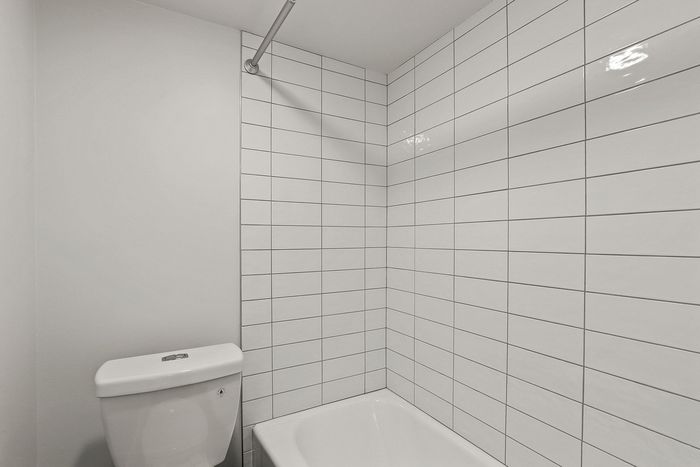 Modern bathroom with elegant white subway tiles and a pristine white bathtub, offering a clean and inviting atmosphere.