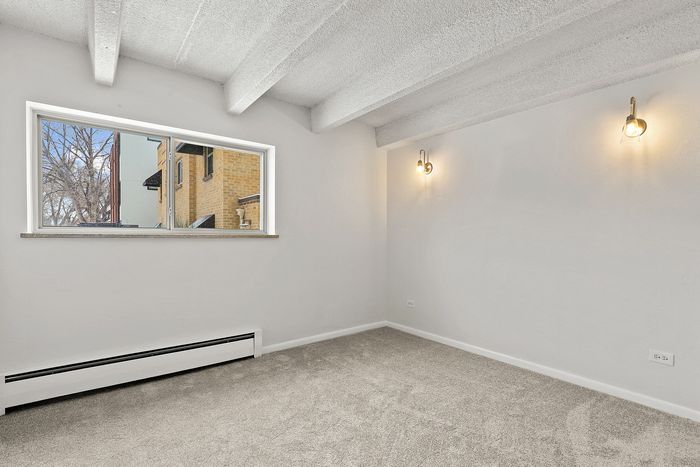 Bright and inviting room with cozy carpet, stylish wall sconces, and a scenic view from the window, perfect for a tranquil living space.