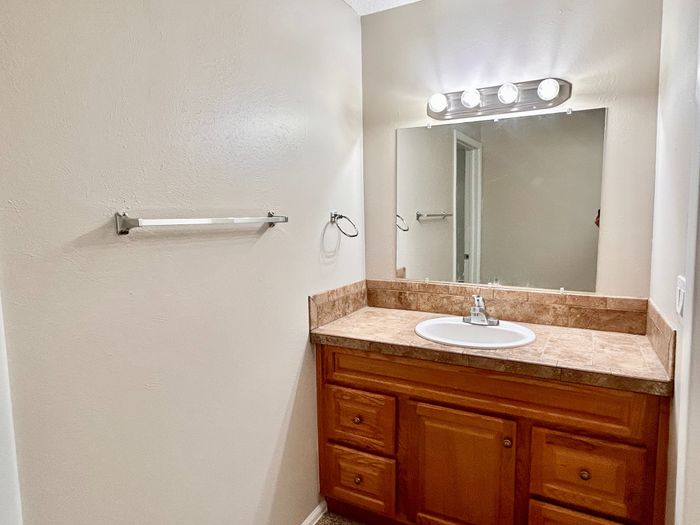 Bright and inviting bathroom with elegant wooden cabinetry, a large mirror, and modern lighting.
