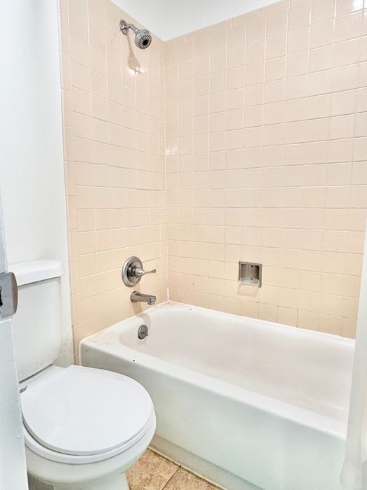 Bright and clean bathroom with modern fixtures, featuring a pristine shower-tub combo and elegant tile work.