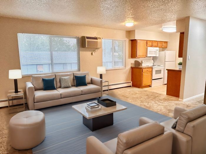 Inviting open-concept living room with cozy seating, natural light, and an adjacent modern kitchen.
