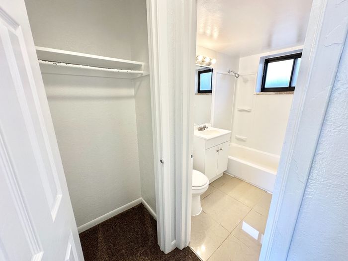 Bright bathroom with modern fixtures, a bathtub, and adjacent cozy closet space, designed for comfortable living.