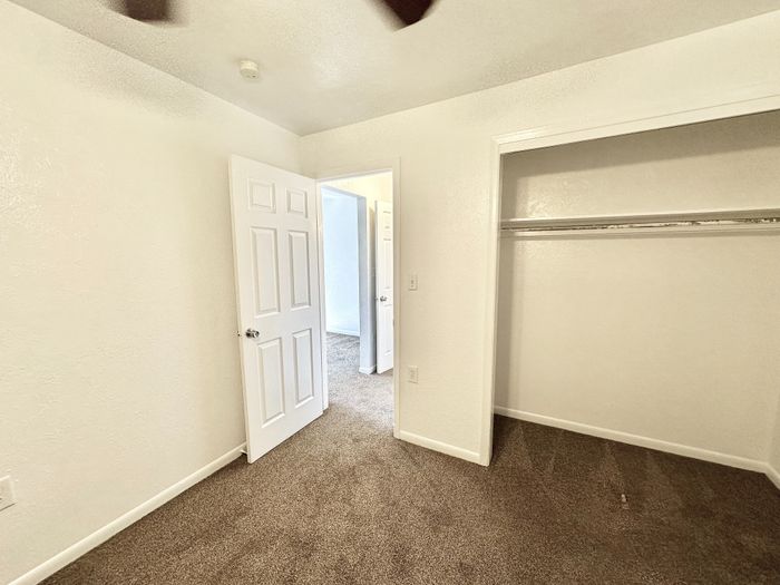 Cozy bedroom with plush carpet and spacious closet, offering a warm and inviting atmosphere.