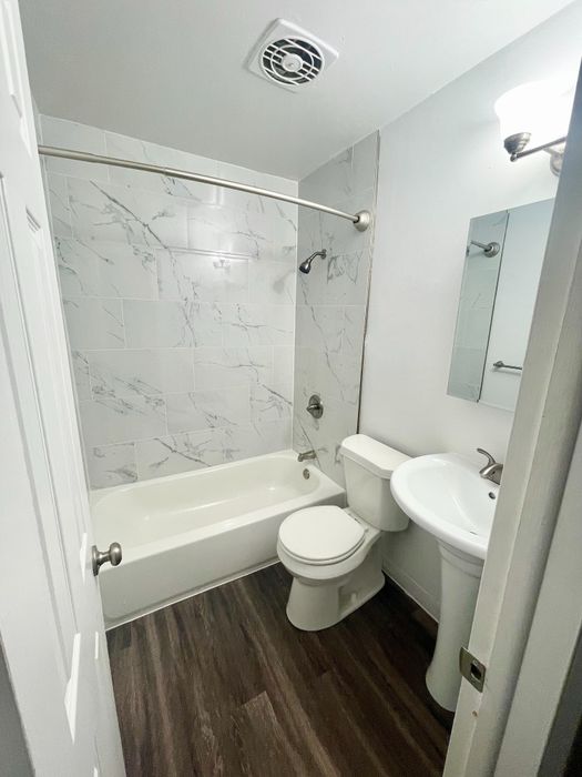 Elegant bathroom featuring a modern design with marble-style tiles, a cozy bathtub, and sleek fixtures.