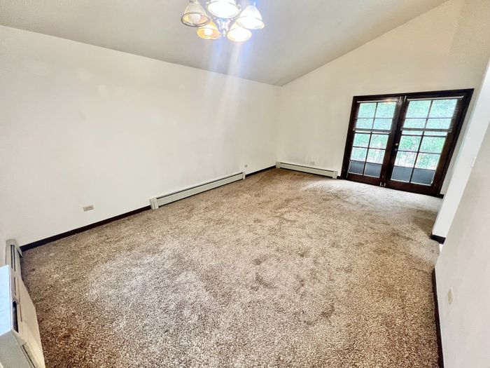 Bright living space with plush carpeting and elegant French doors, offering a cozy and inviting atmosphere.